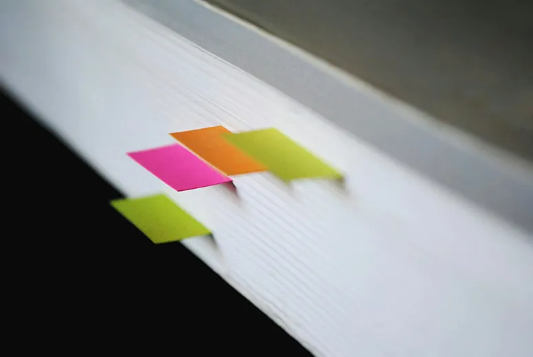 Seitenansicht eines Buches mit bunten Post-Its